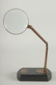 A BRASS MAGNIFYING GLASS on an oval base.