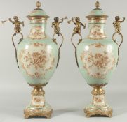 A PAIR OF SEVRES DESIGN PORCELAIN URN SHAPED VASES painted with flowers and gilt cupids. 20ins
