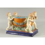 A MAJOLICA DESIGN POTTERY PLANTER a bowl held by four cupids on a blue base. 12ins high.