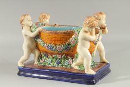 A MAJOLICA DESIGN POTTERY PLANTER a bowl held by four cupids on a blue base. 12ins high.