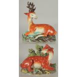 TWO LARGE STAFFORDSHIRE SEATED DEER with spots on rustic bases 7ins & 4.5ins.
