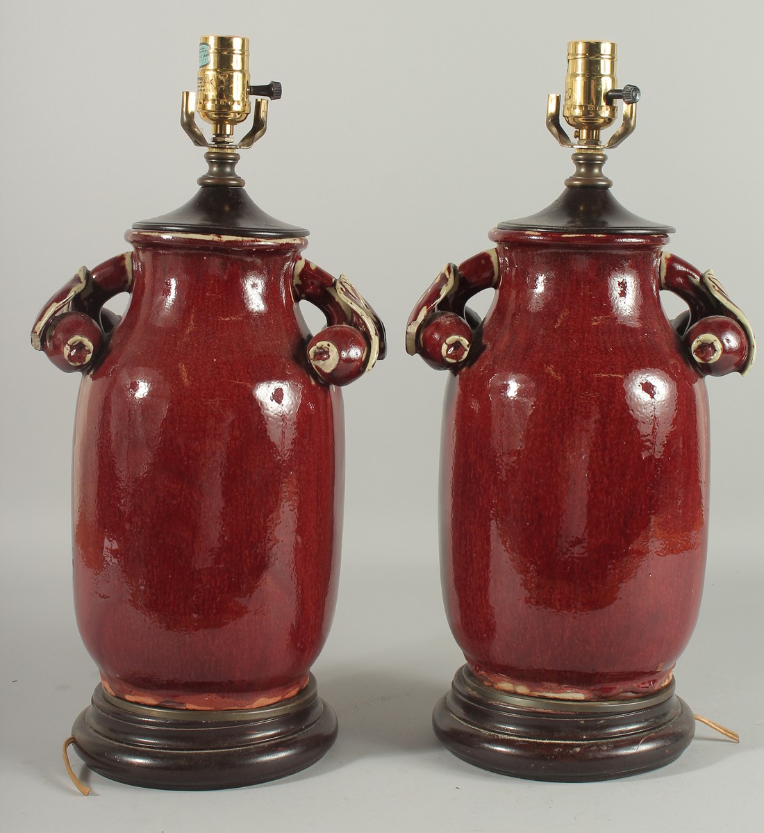 A PAIR OF CHINSE SANG DE BOEUF PORCELAIN LAMPS. 18ins high.