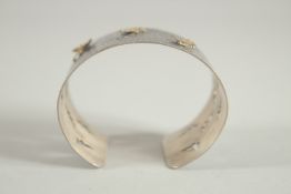 A HALLMARKED STERLING SILVER OXIDISED HAMMERED BANGLE, mounted with gilded butterflies.