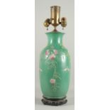A CHINESE GREEN GROUND PORCELAIN LAMP on a wooden stand. 16ins high.