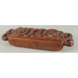 A MAORI LONG CARVED WOOD FOOD VESSEL carved with masks and mother of pearl eyes. 13ins high.