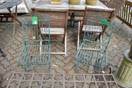 A pair of wrought iron folding chairs.