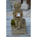 A small garden ornament modelled as a boy seated reading a book.