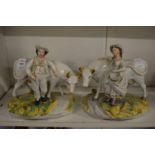 A pair of Staffordshire figures of farmer and milk maid, each standing by a cow.
