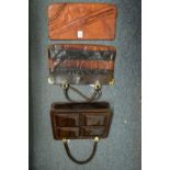 A ladies tan leather clutch bag and two alligator handbags.