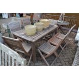 A rectangular wooden garden table with seven folding chairs.