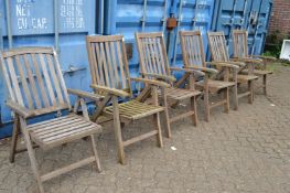 A set of five teak garden reclining armchairs and another similar.