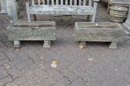 A pair of reconstituted stone rectangular garden troughs on pedestal bases.