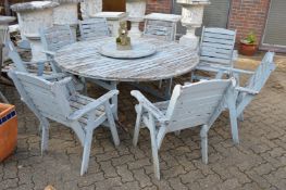 A large painted circular garden table and eight armchairs.