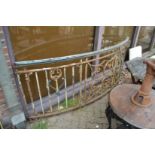A large curved wrought iron section of a balustrade with copper hand rail.