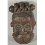 AN AFRICAN CARVED WOOD TRIBAL MASK, the head with three toads, 26cm x 22cm.