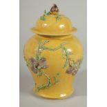 A CHINESE QING DYNASTY YELLOW GROUND SANCAI GINGER JAR AND COVER, relief decorated with blossoming