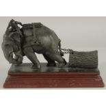A FINE INDIAN BRONZE FIGURE OF AN ELEPHANT, pulling a tree trunk on chains with a man seated atop,