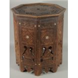 A SYRIAN OCTAGONAL WOODEN TABLE, with mother of pearl inlay to the sides and carved panels of