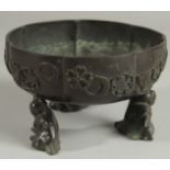 A JAPANESE BRONZE PETAL FORM BOWL, raised on three mounted figural feet, the bowl with relief mon