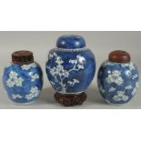THREE CHINESE BLUE AND WHITE PRUNUS JARS AND COVERS, two with wooden covers and one with wooden