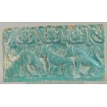 A 12TH CENTURY PERSIAN KASHAN TURQUOISE GLAZED POTTERY TILE, with relief felines, 35.5cm x 19.5cm.