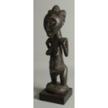 AN AFRICAN CARVED WOOD LUBA-HEMBA ANCESTOR FIGURE, mounted to a wooden base, 44cm high overall.