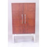 A TAN LEATHER AND CHROME BAR CABINET with double panel doors 5ft 4ins high, 3ft wide, 1ft 4ins