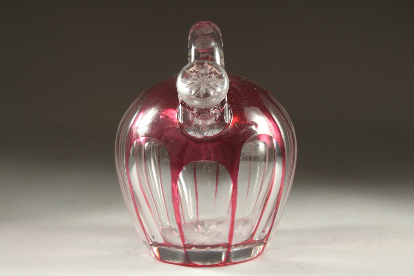 A SLICE CUT RUBY TINTED GLASS EWER with stopper. 7ins high. - Image 2 of 5