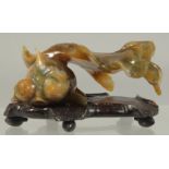 A CARVED COLOURED JADE FISH. 3ins long on a wooden base.