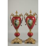 A GOOD PAIR OF BRONZE AND PORCELAIN RED FLORAL TWO HANDLED URNS. 18ins high.