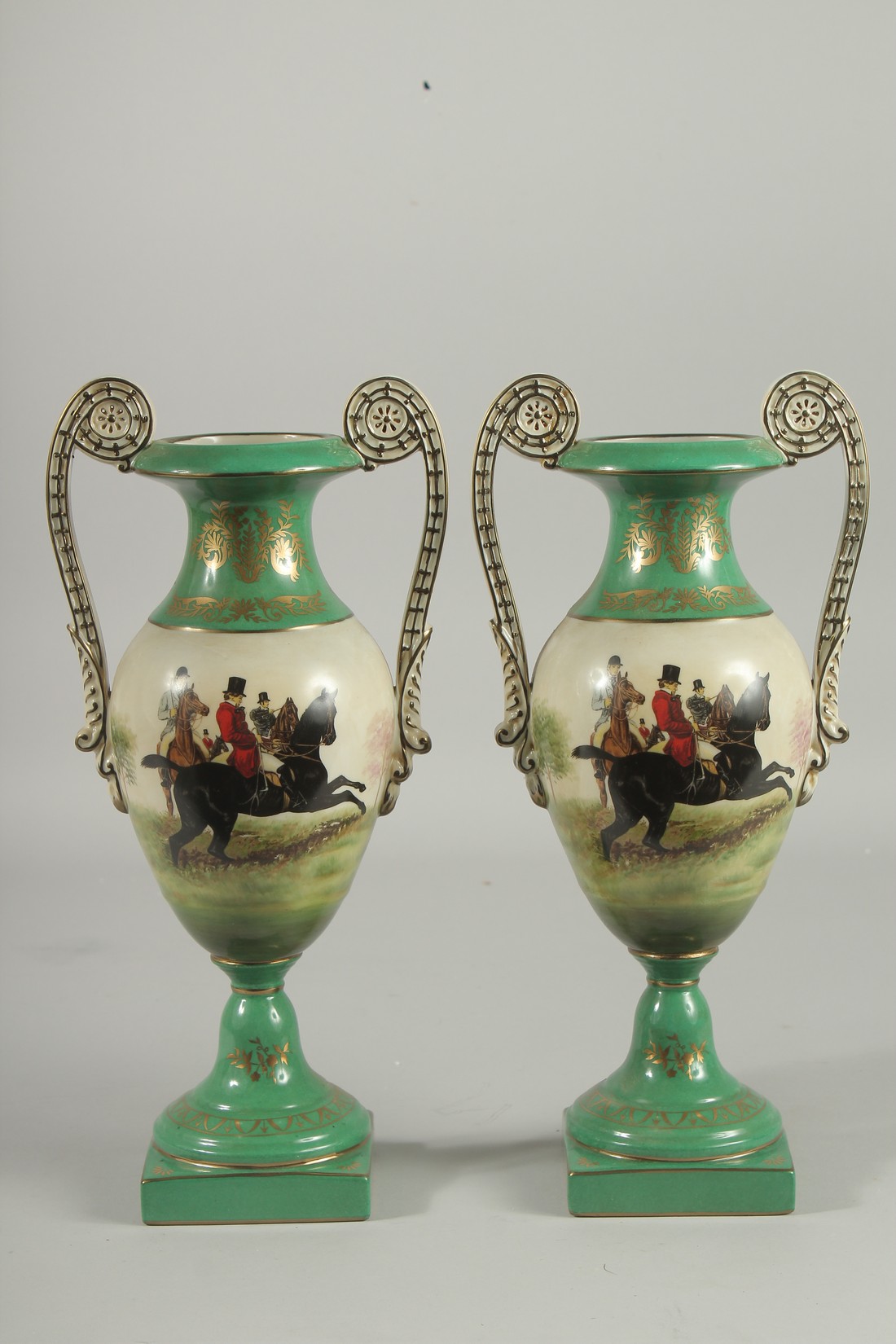 A PAIR OF SEVRES DESIGN TWO HANDLED GREEN HUNTING VASES. 13ins high.