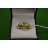 An 18ct gold ring set with a single central emerald flanked by diamonds to the shoulders size Q.