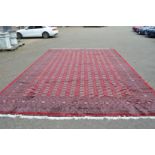 A good large modern crimson ground Bokara carpet 580cm x 380cm.
