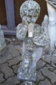 A composite garden ornament modelled as a cherub holding a bowl of fruit.