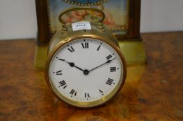 A small brass circular bedside clock with enamel dial.