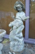 An unusual two part composite garden statue modelled as a young boy seated on a rocky outcrop (one