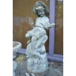 An unusual two part composite garden statue modelled as a young boy seated on a rocky outcrop (one