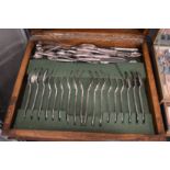 An oak cutlery canteen containing various plated flatware.