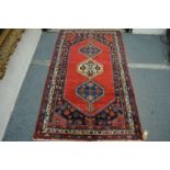 A good small Persian design rug, crimson ground with three central large motifs 185cm x 110cm.