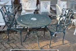 A green painted aluminium circular patio table with a pair of armchairs.