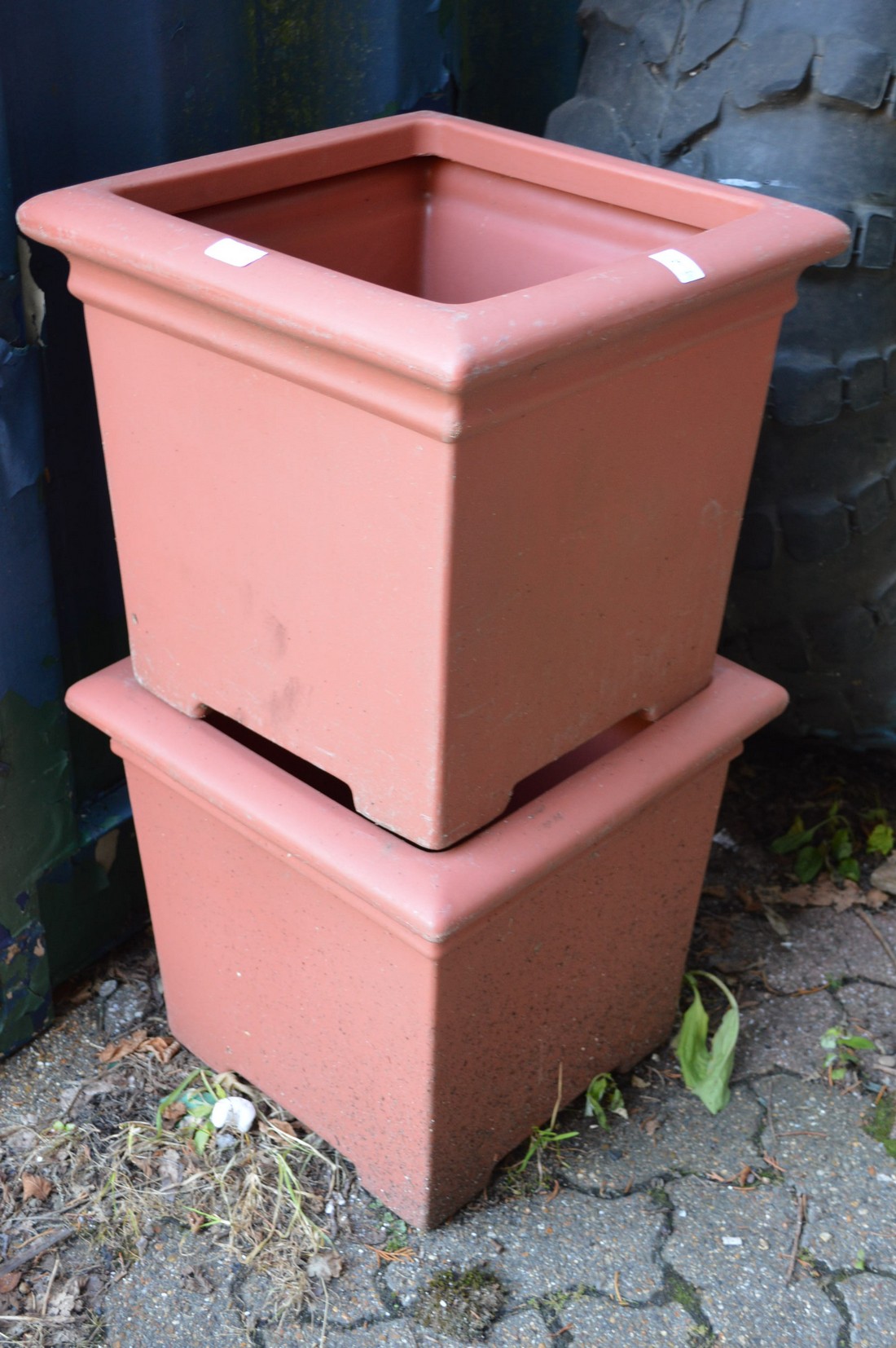 A pair of plastic square shaped garden planters.