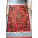 A Persian design rug, red ground with stylised floral decoration 122cm x 86cm.