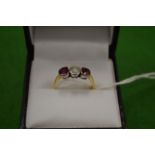 An 18ct gold diamond and ruby three stone ring size M½.
