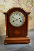 An Edwardian inlaid mahogany mantle clock with column supports to the case.