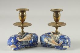 A PAIR OF BLUE AND WHITE PORCELAIN BRASS MOUNTED FIGURAL CANDLESTICKS, the porcelain bases formed as