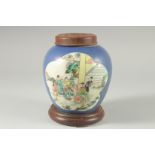 AN EARLY 20TH CENTURY CHINESE BLUE GROUND FAMILLE VERTE PORCELAIN JAR, with wooden cover and stand.