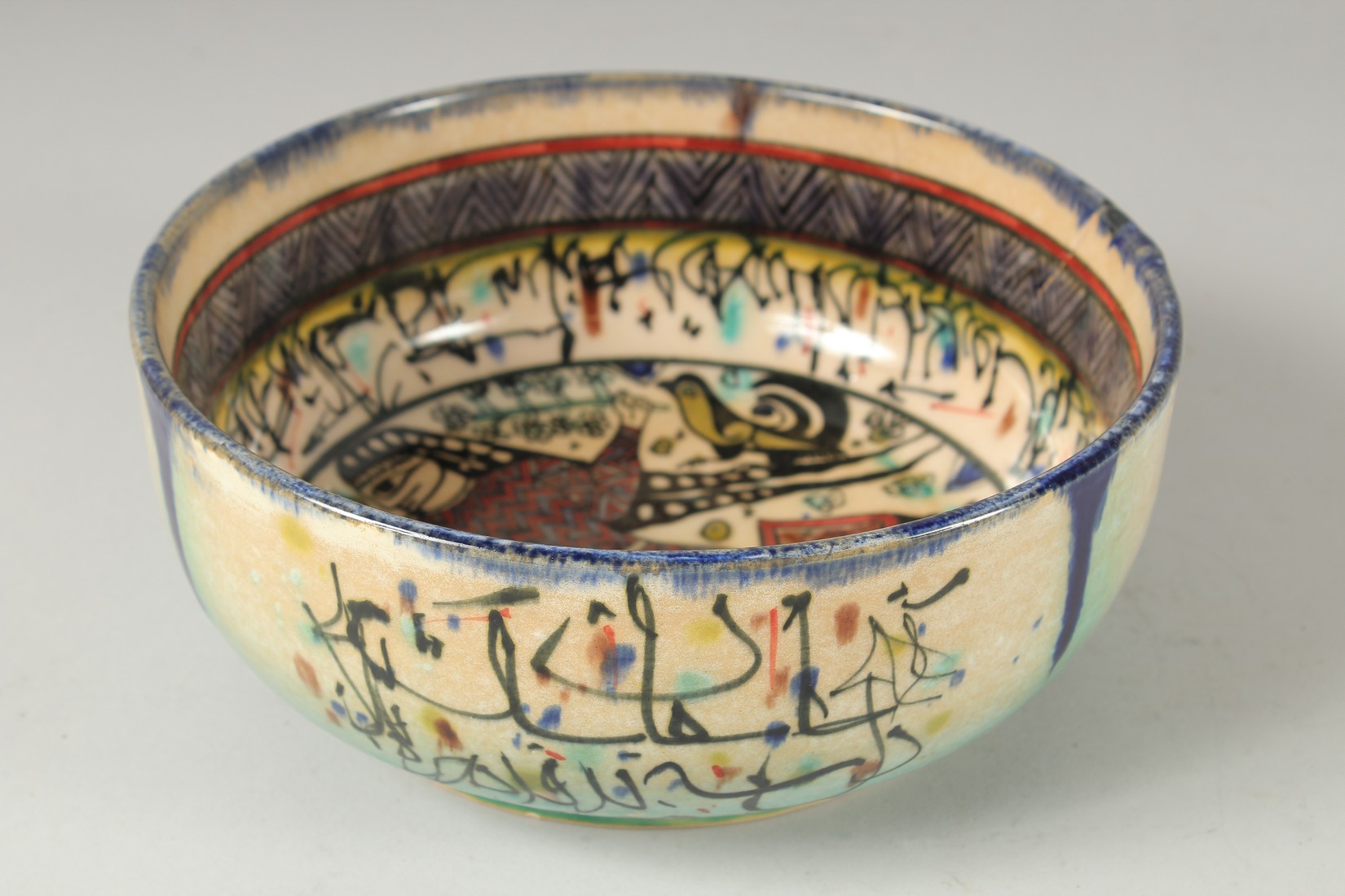 A VINTAGE KHOROSAN STYLE GLAZED POTTERY BOWL, painted with a figure and calligraphy, 21cm diameter.