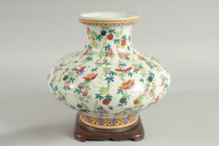 A CHINESE FAMILLE ROSE PORCELAIN SQUAT-FORM VASE and hardwood stand, the vase decorated all over