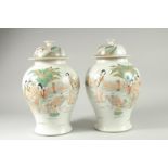 A PAIR OF CHINESE FAMILLE VERTE PORCELAIN JARS AND COVERS, decorated with females and children in