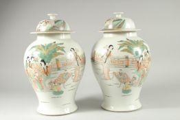 A PAIR OF CHINESE FAMILLE VERTE PORCELAIN JARS AND COVERS, decorated with females and children in
